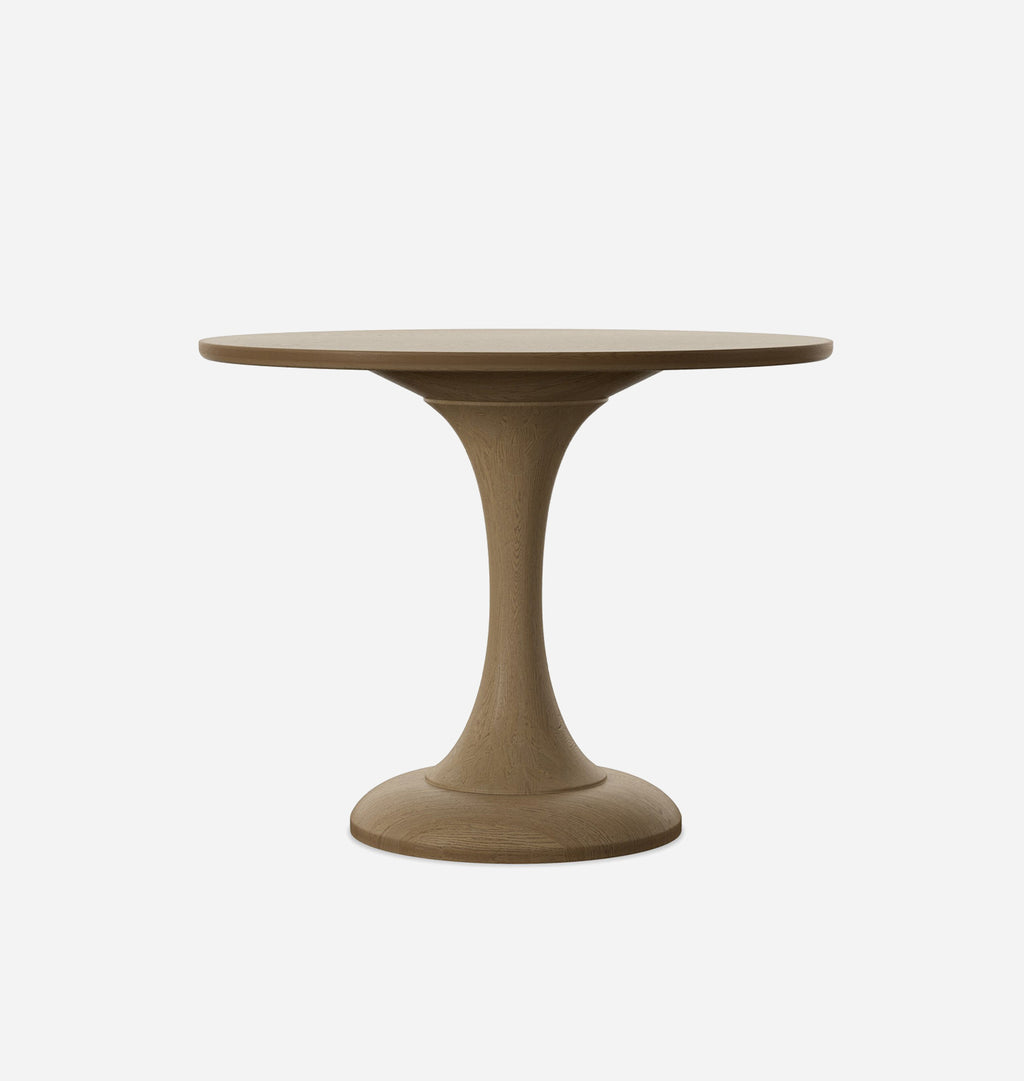 A round pedestal dining table with a smooth, matte finish in a warm taupe-brown color, shown against a plain light gray background.