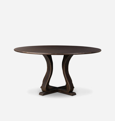A round dark wood dining table with a sculptural, curved trestle-style base, shown against a plain light gray background.
