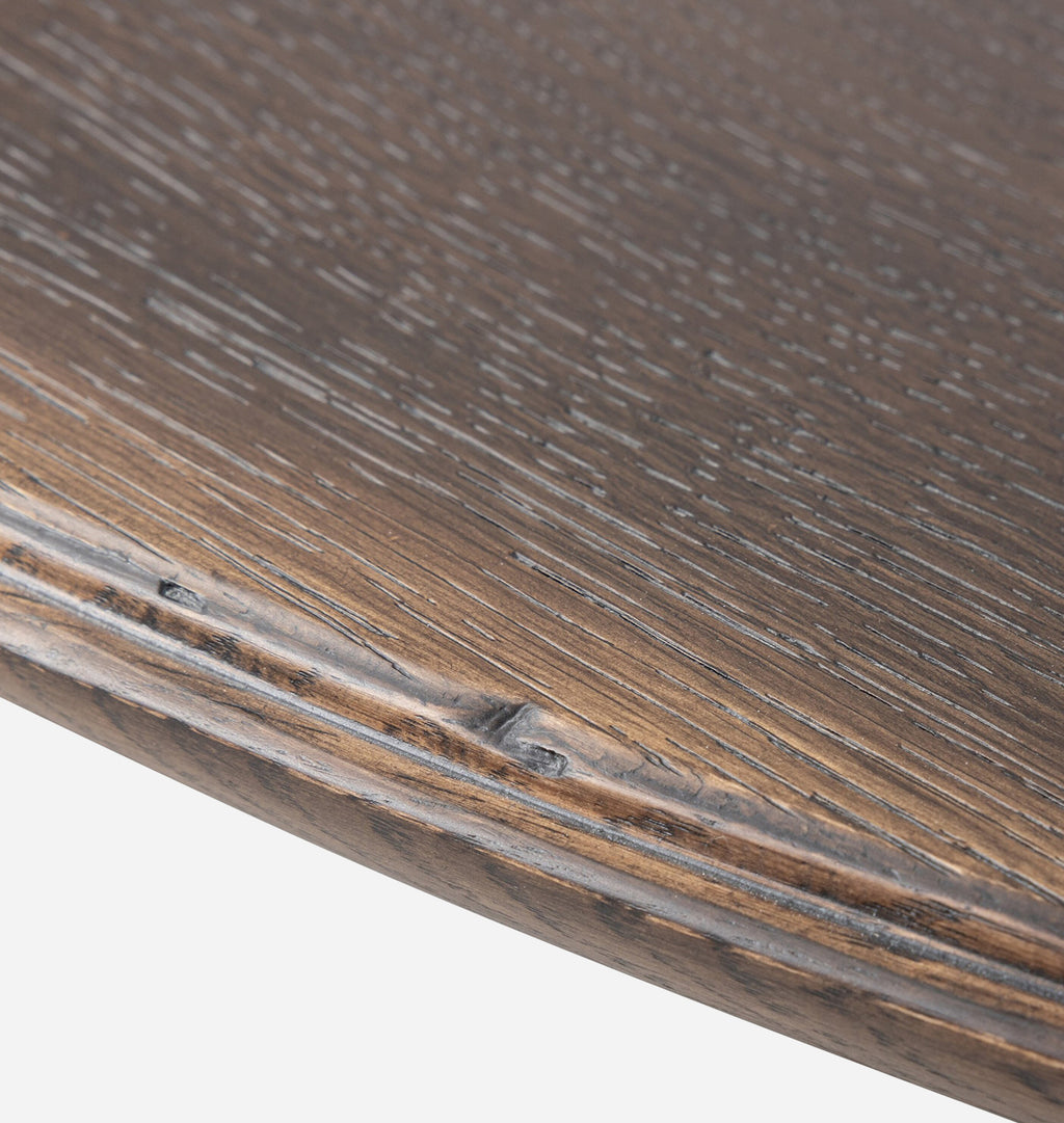 Close-up of a dark brown wooden surface with visible wood grain texture and a curved edge, shown against a light neutral background.