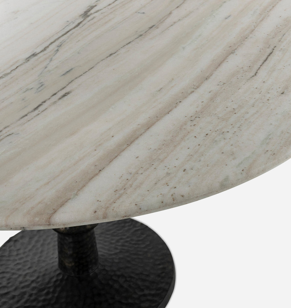 Close-up of a round white marble tabletop with natural gray veining and a hammered black metal pedestal base on a white background.