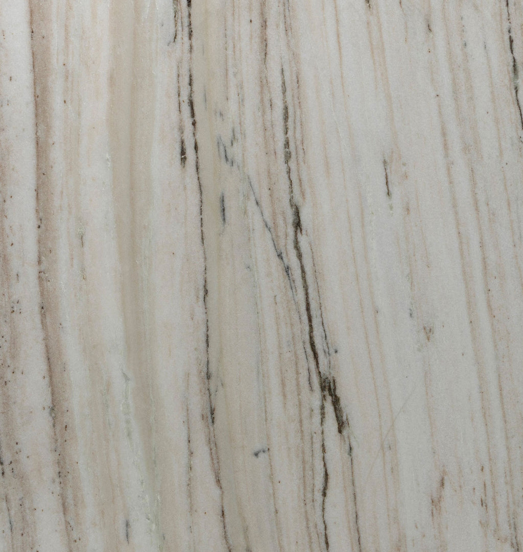 A close-up texture of a light beige stone surface with vertical veining in cream, tan, and dark brown.