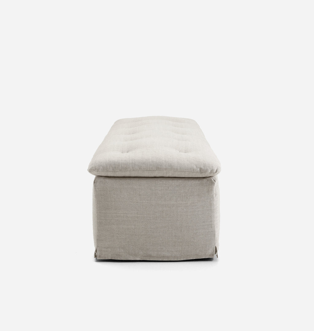 A light beige upholstered bench with a tufted cushioned top, shown from the front against a plain white background.