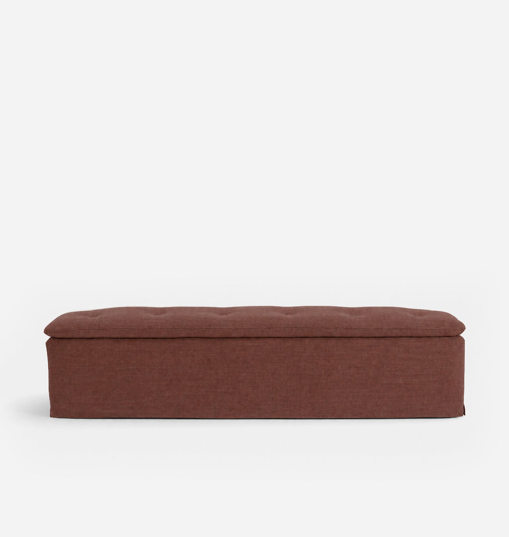 A rectangular upholstered bench with a tufted lid in a warm rust-brown fabric, shown against a plain white background.