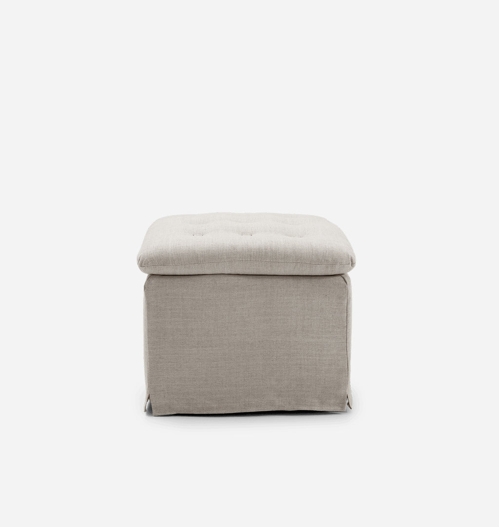 A square upholstered ottoman stool with a tufted cushion on top, shown against a plain light gray background.