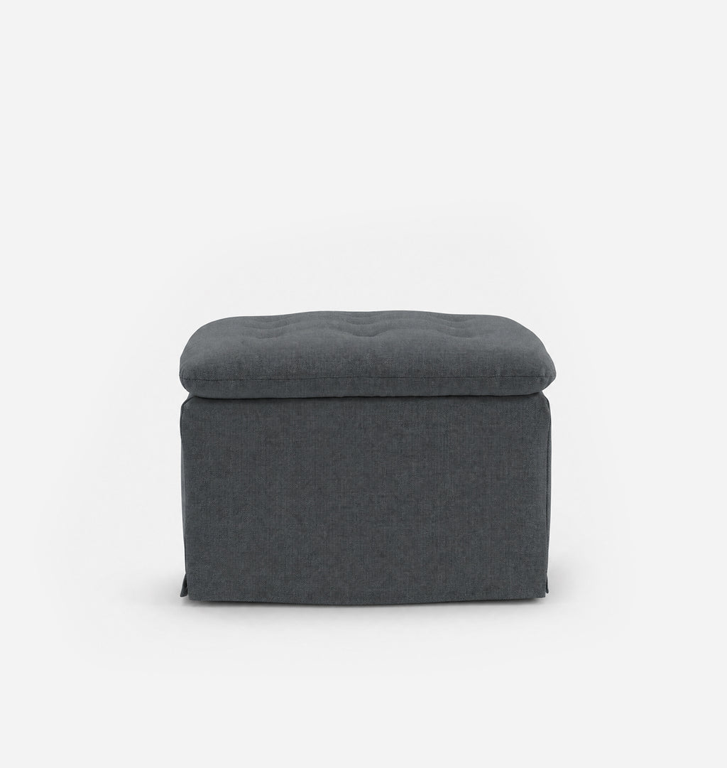 A dark gray fabric ottoman with a tufted top, shown against a plain white background.