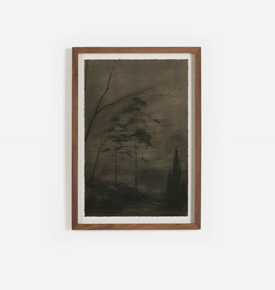 A framed dark monochrome landscape artwork with silhouetted trees, mounted on a white wall in a medium brown wooden frame.