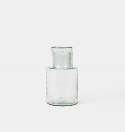 A clear glass vase with a textured, hammered finish and a flared rim, shown against a plain light gray background.