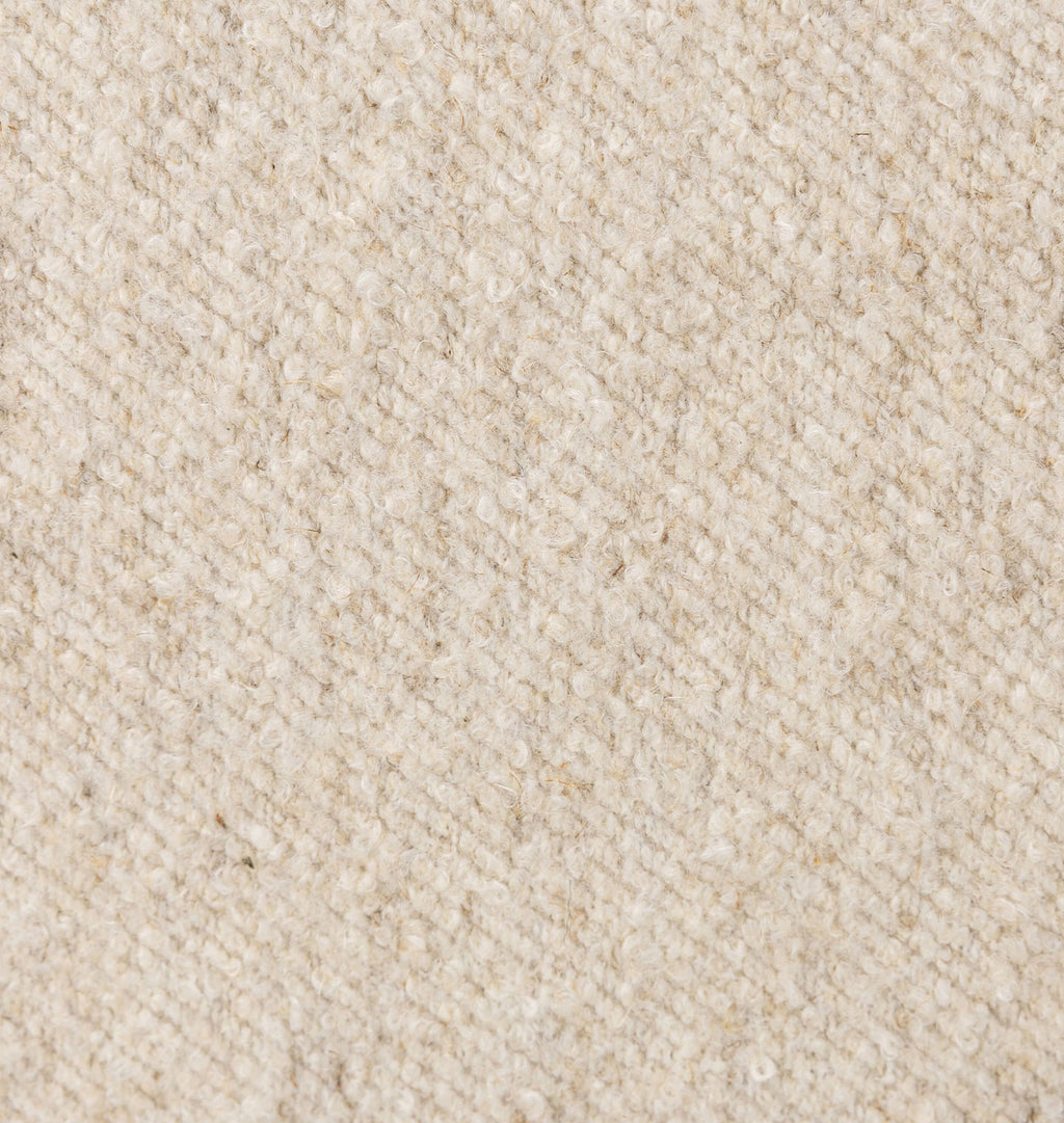 A close-up texture shot of a woven fabric in a warm cream or off-white color, showing the detailed diagonal weave pattern.