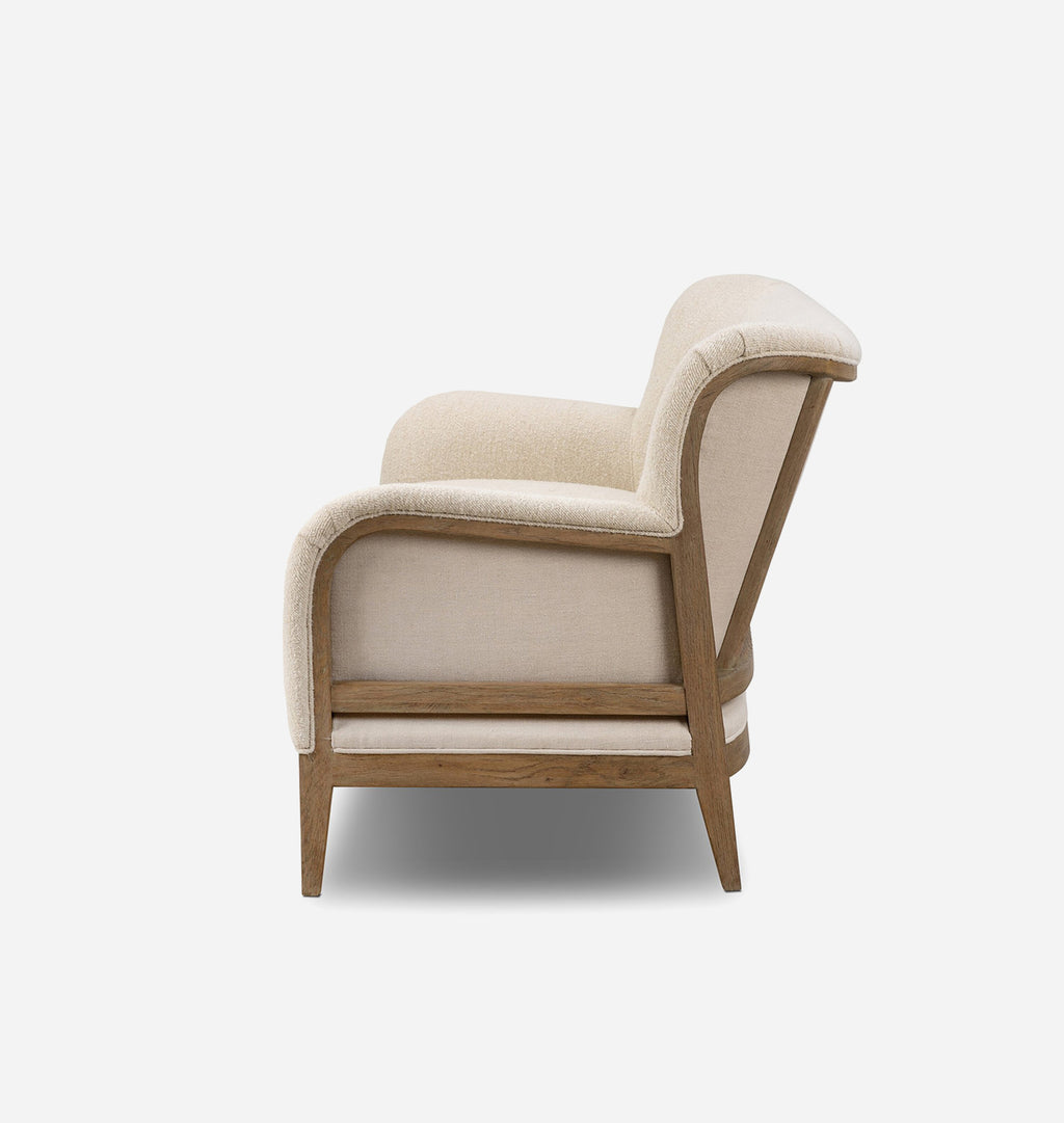 A modern accent chair with beige textured upholstery and a light brown wooden frame, shown from a side profile view against a plain white background.
