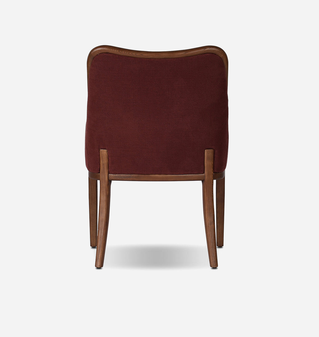 A modern dining chair with a deep burgundy velvet upholstered seat and backrest, supported by a warm brown wooden frame with tapered legs, shown from the rear against a light gray background.