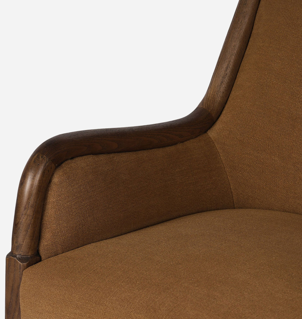Close-up of an upholstered armchair corner showing warm brown textured fabric and a dark wood frame against a light gray background.