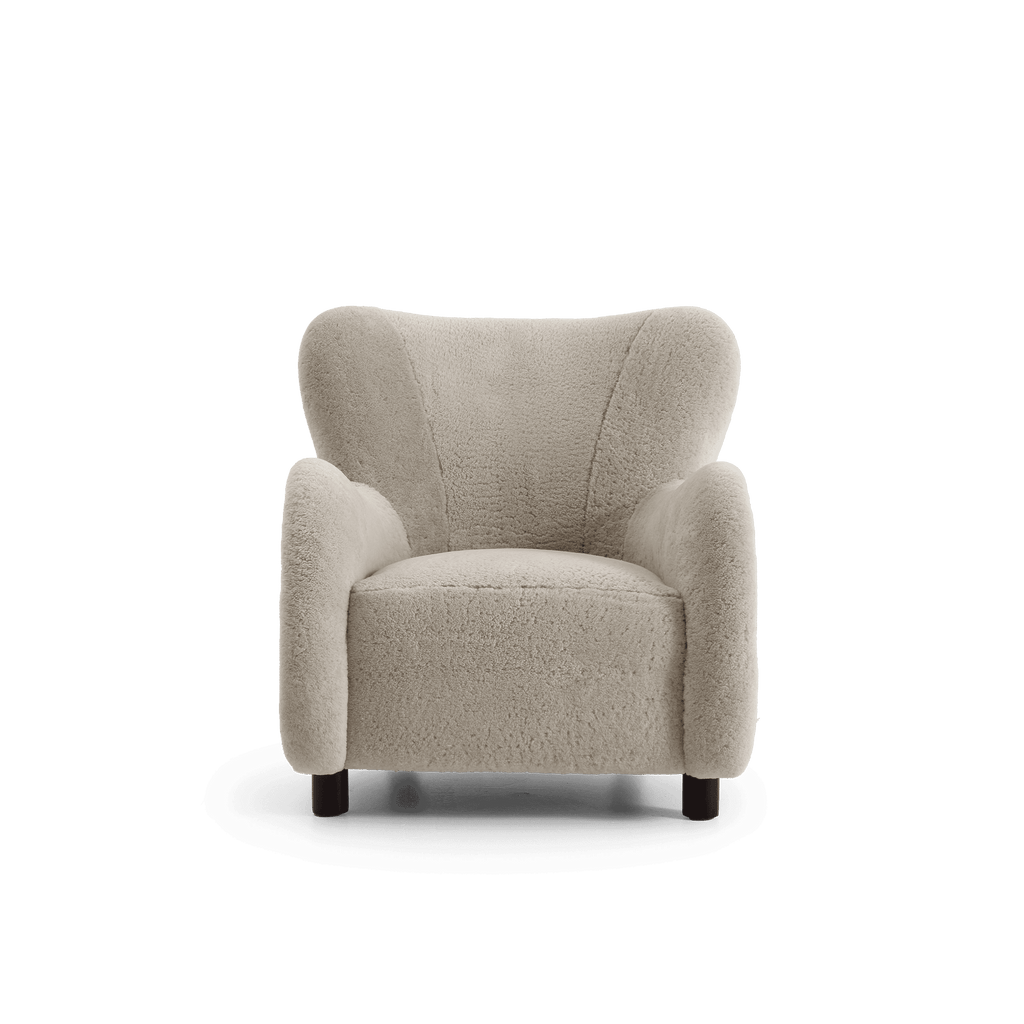 A modern barrel-style armchair upholstered in a light beige shearling, featuring dark wooden legs, shown against a plain white background.