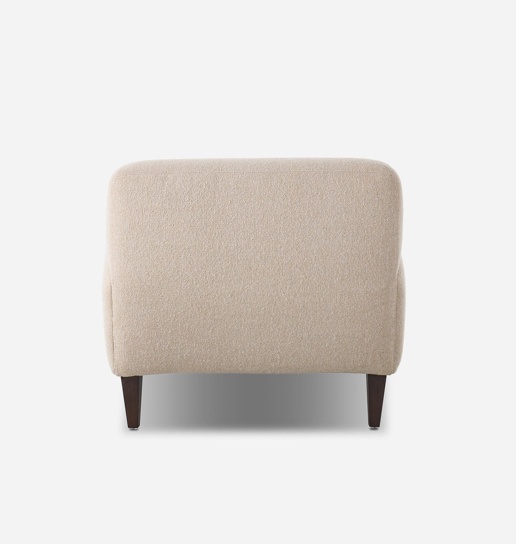 A modern low-profile armchair with a textured beige bouclé fabric upholstery and dark brown tapered wooden legs, shown from a straight-on front angle against a plain white background.