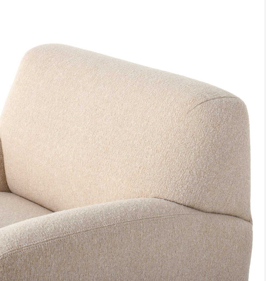 Close-up of a beige upholstered armchair showing the textured fabric and curved backrest against a plain white background.