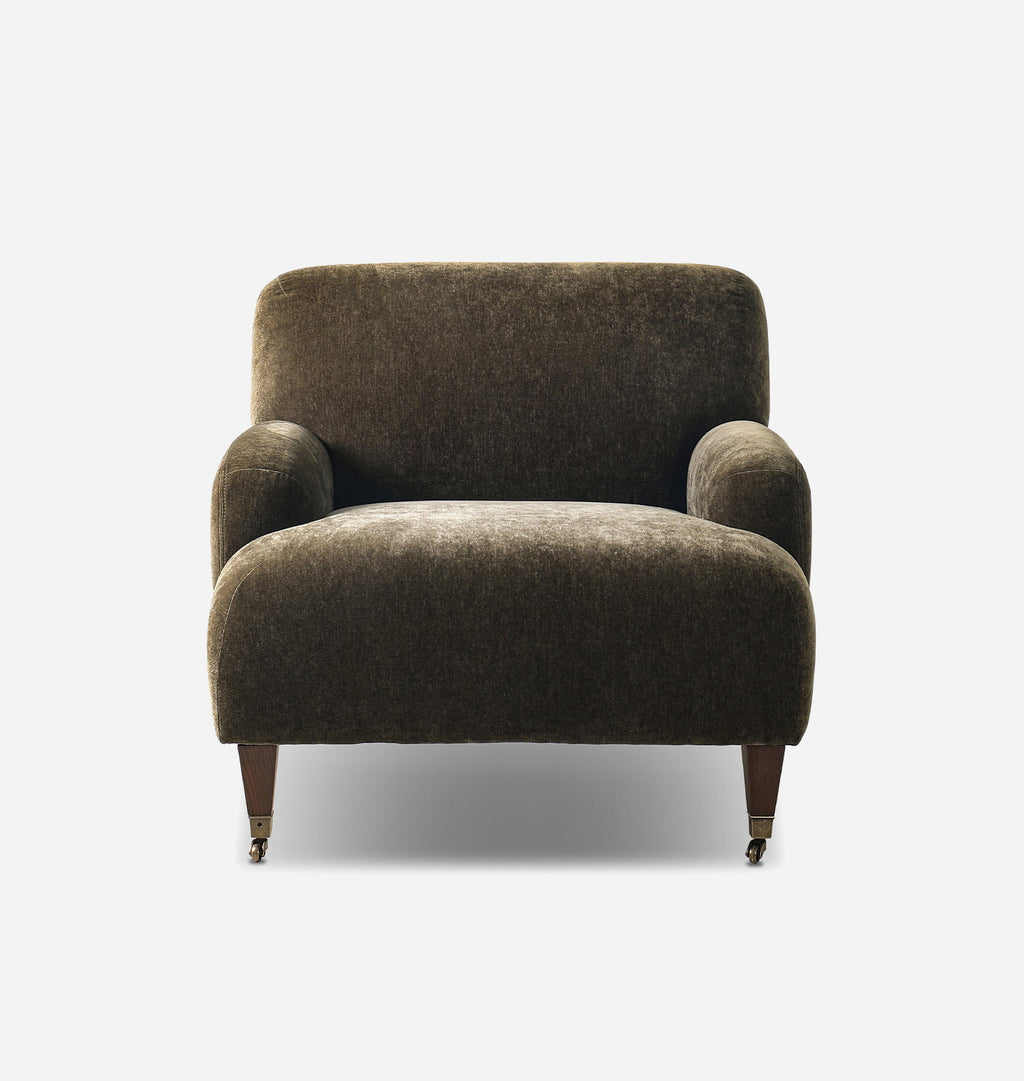 A single upholstered armchair with rounded arms, a high back, and tapered dark wooden legs, shown against a plain light gray studio background.