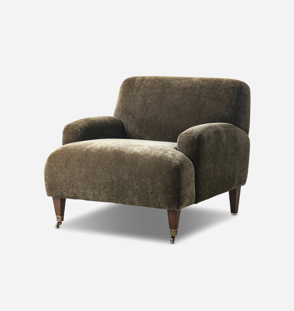A mid-century modern armchair upholstered in textured olive velvet, featuring tapered dark wood legs with brass casters, shown against a plain light gray background.