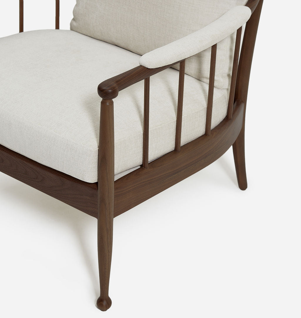 Close-up of a modern armchair with a dark brown wooden frame and light beige textured fabric cushions, shown on a clean white background.