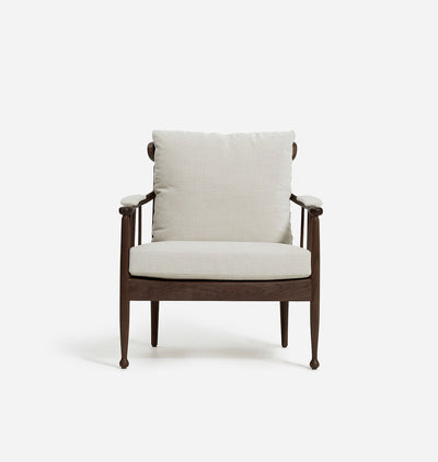 A modern accent chair featuring a dark brown wooden frame with tapered legs and curved armrests, upholstered with a light beige textured fabric cushion on the seat and backrest, set against a plain white background.