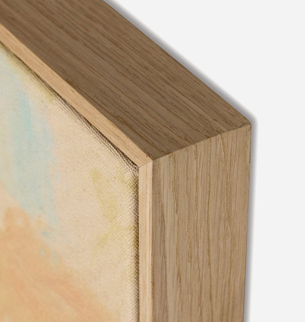 Close-up detail of a framed canvas painting corner, showing the light natural wood frame and textured canvas surface against a white background.