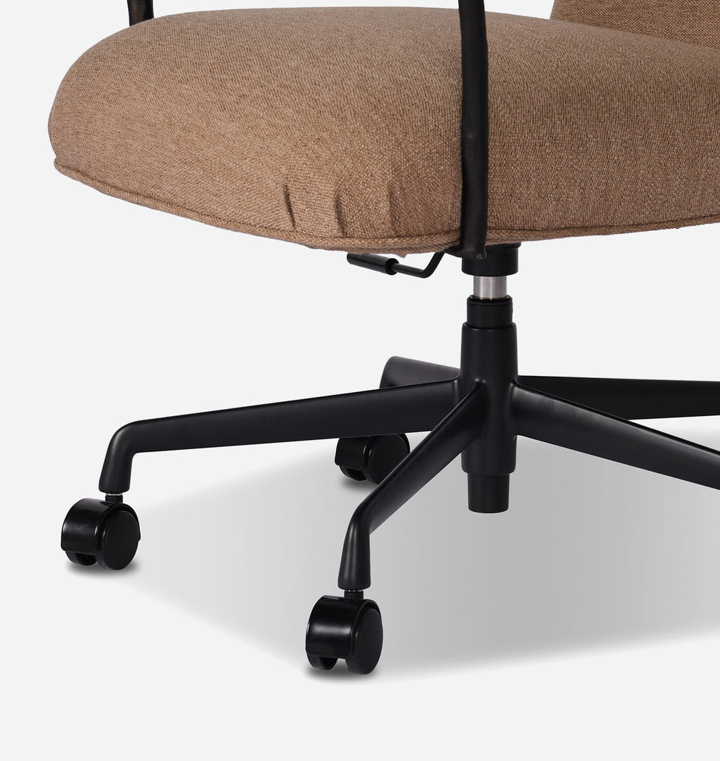 Close-up of an office chair showing the upholstered seat cushion in a warm taupe-brown fabric, a black five-star base, and dual-wheel casters on a light gray studio background.