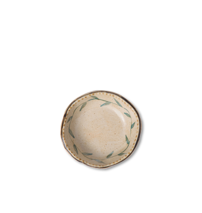 Overhead view of a round ceramic salt bowl with an organic rim, decorated with a green leafy vine border and a gold dotted accent line on a white background