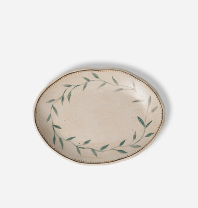 An oval ceramic serving platter with a speckled beige glaze, decorated with a hand-painted green leafy wreath border, shown on a clean white background.