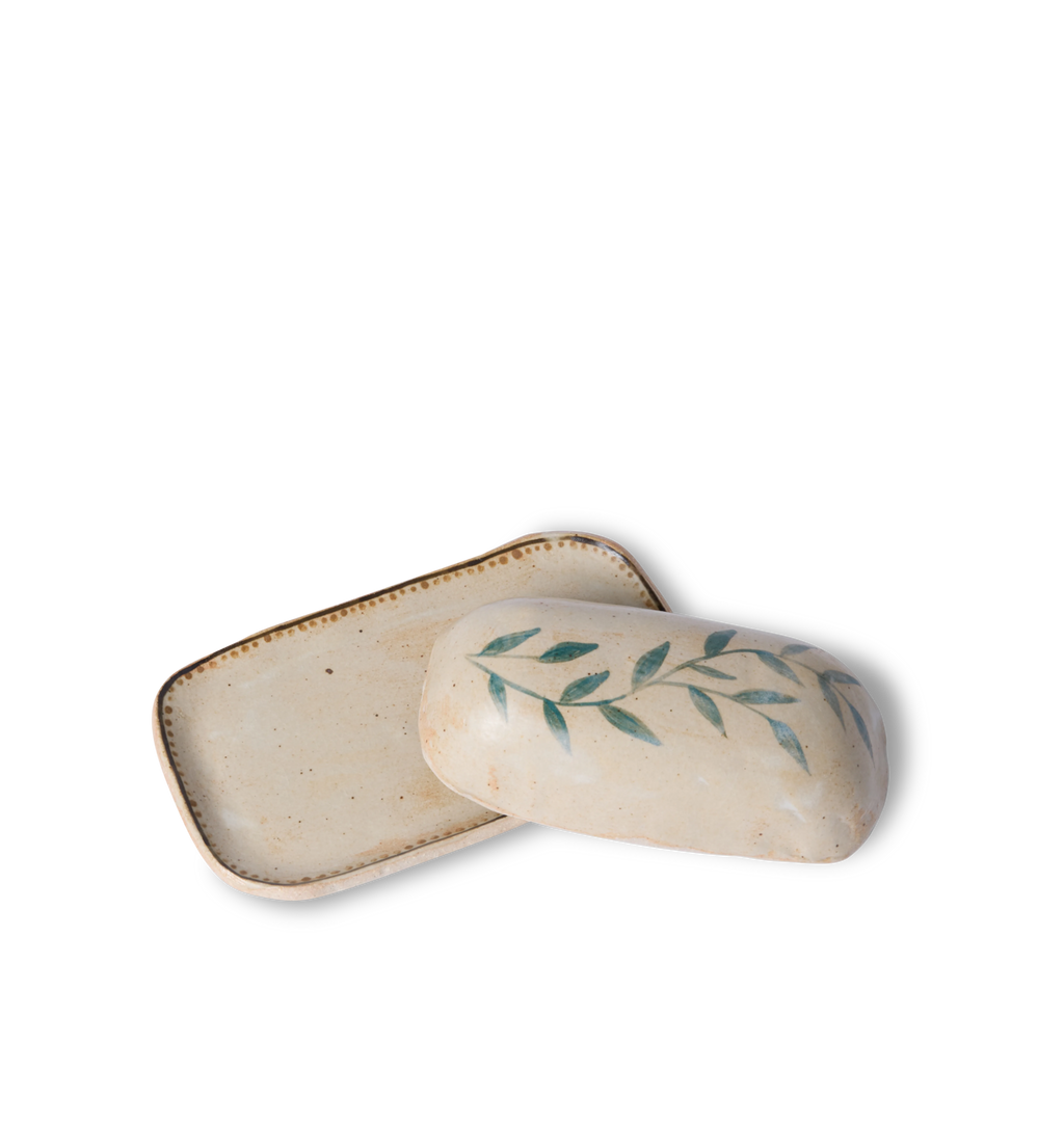 Open view of a ceramic butter dish and lid decorated with a green leafy vine border and a gold dotted accent line on a white background