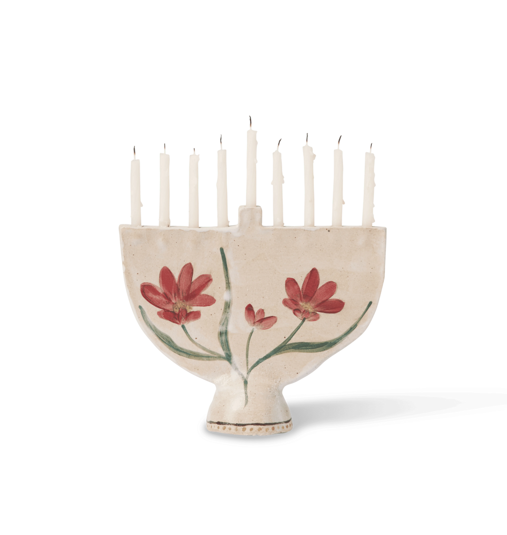 A hand-painted ceramic cream-colored menorah with red flowers and green leaves on a white background.