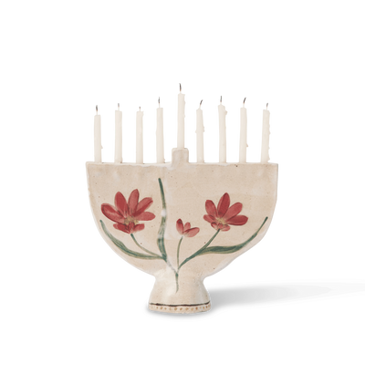 A hand-painted ceramic cream-colored menorah with red flowers and green leaves on a white background.