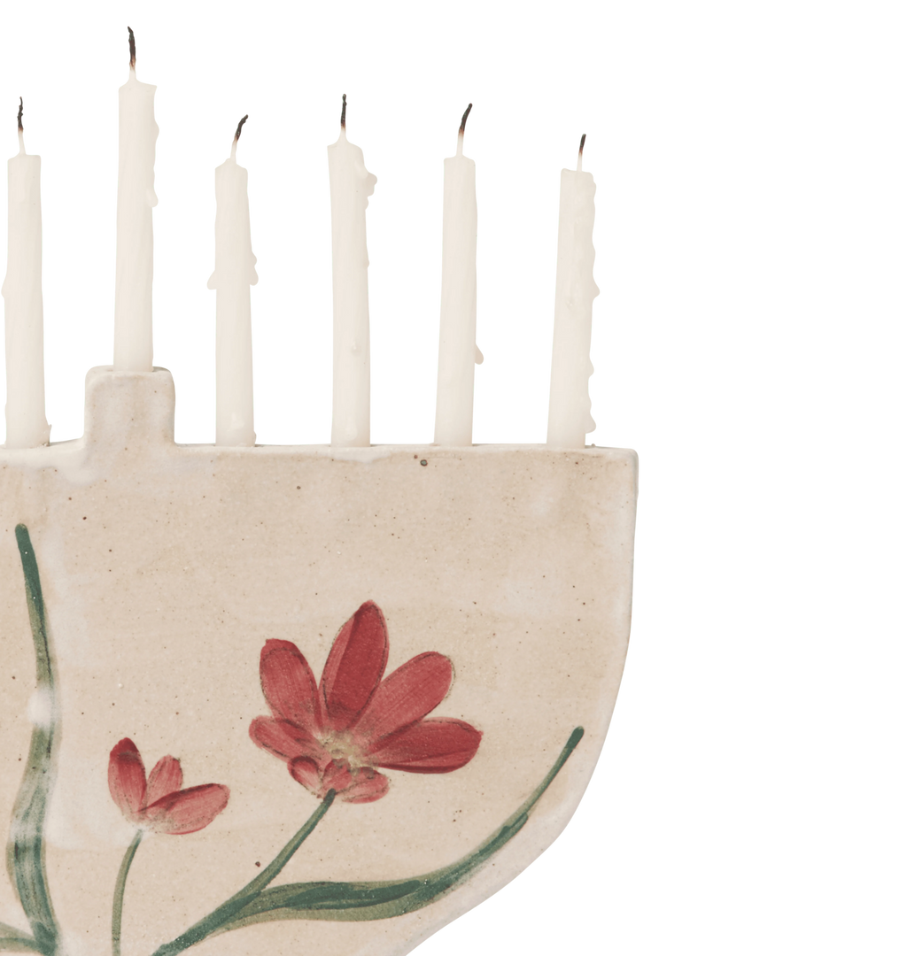 A hand-painted ceramic cream-colored menorah with red flowers and green leaves on a white background.