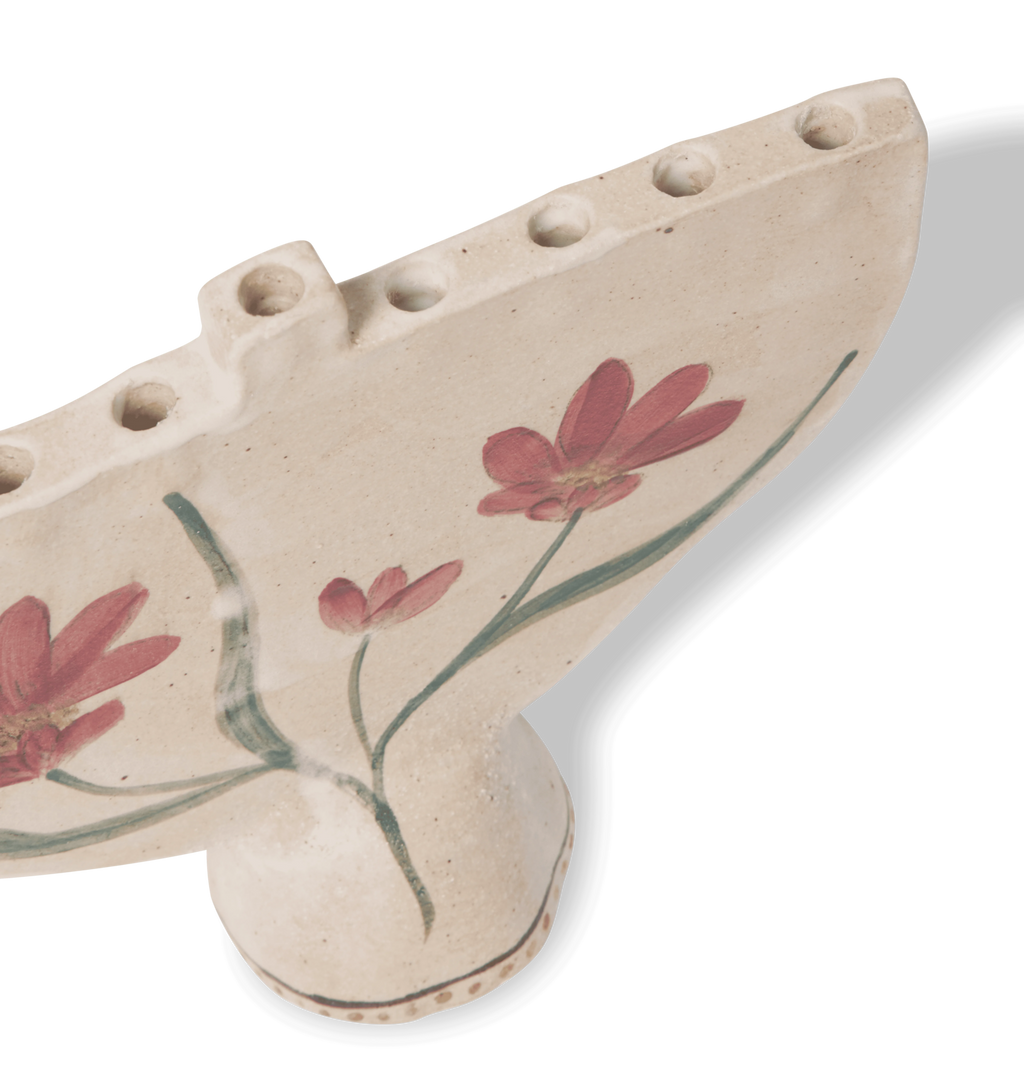 A hand-painted ceramic cream-colored menorah with red flowers and green leaves on a white background.