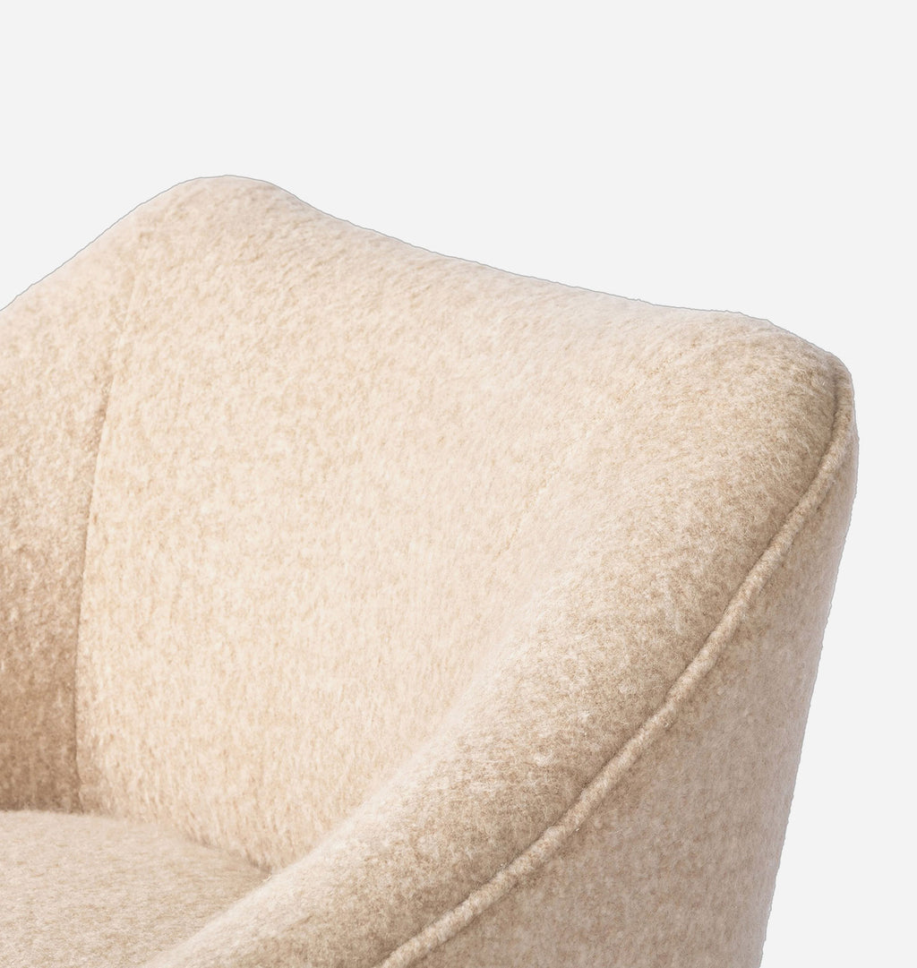 Close-up of a beige upholstered armchair showing the textured fabric and curved arm detail against a plain light background.