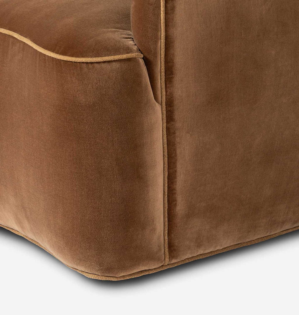 Close-up of a brown velvet upholstered furniture corner with tan contrast piping, showing the fabric texture and stitching detail.