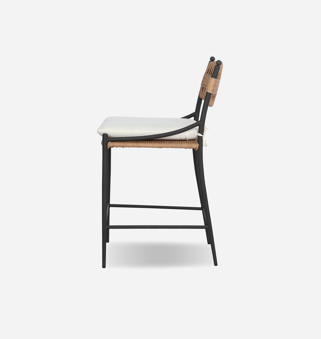 A modern counter stool with a black metal frame, woven natural backrest and seat, and a white upholstered seat cushion, shown from a side profile view against a light gray background.