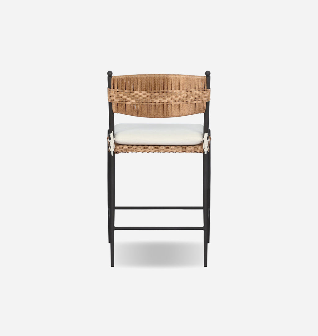 A modern bar stool with a black metal frame, a natural woven backrest, a cream-colored seat cushion, and white decorative accents on the sides, shown against a plain light gray background.