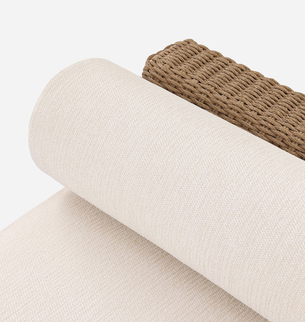 A close-up of a rolled cream-colored woven fabric or canvas material, with a brown woven strip visible along the top edge, photographed on a clean white background.