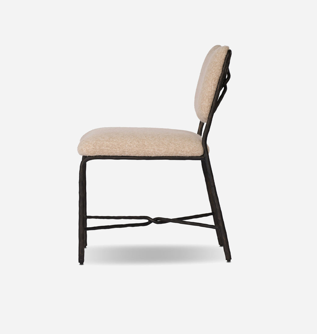 A modern dining chair with a textured beige upholstered seat and backrest, supported by a black metal frame with a decorative twisted crossbar on the legs, shown against a plain white background.