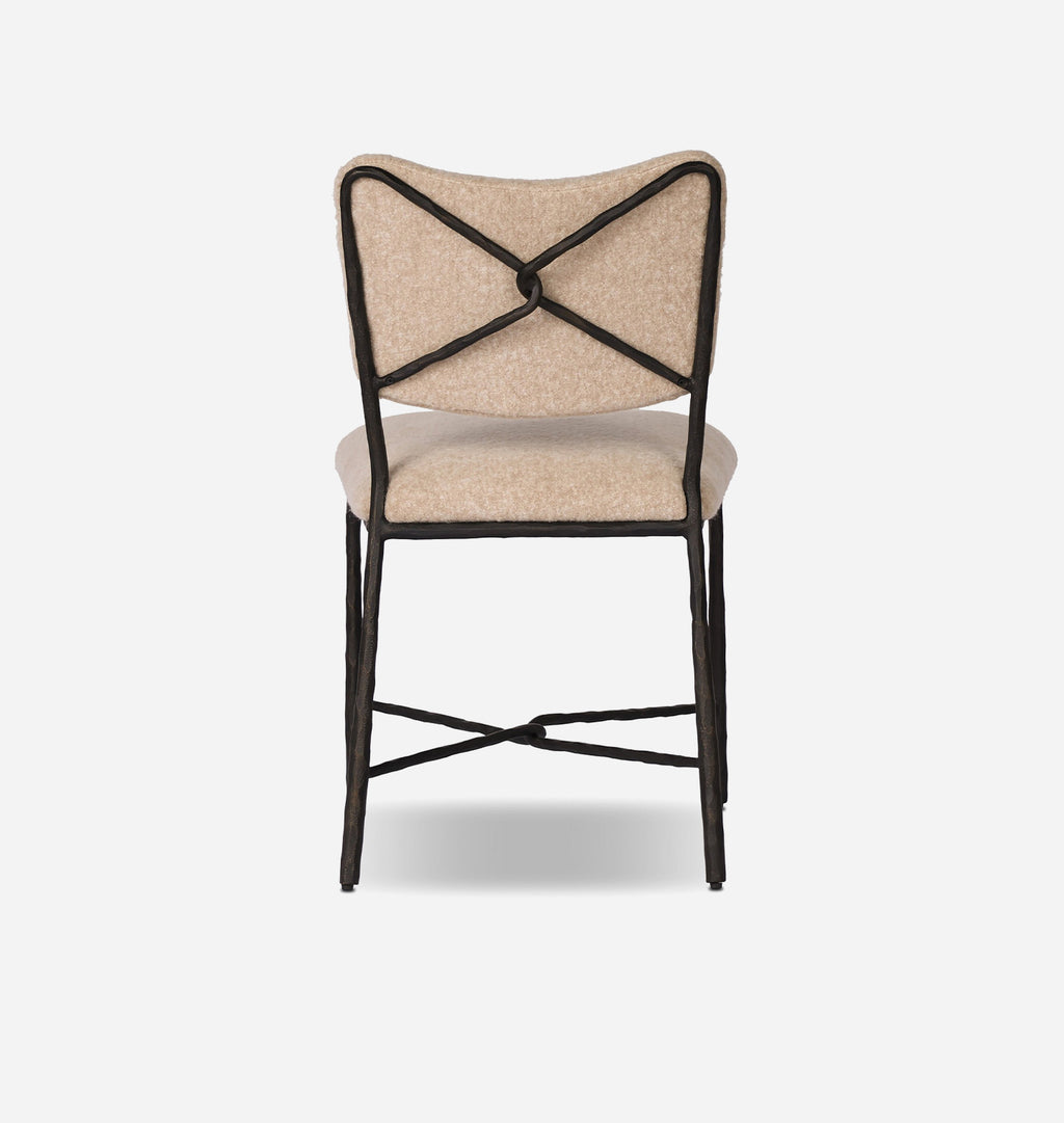 A modern dining chair with a textured beige fabric seat and backrest, featuring a black metal frame with an X-back design and crossed leg supports, shown against a plain white background.