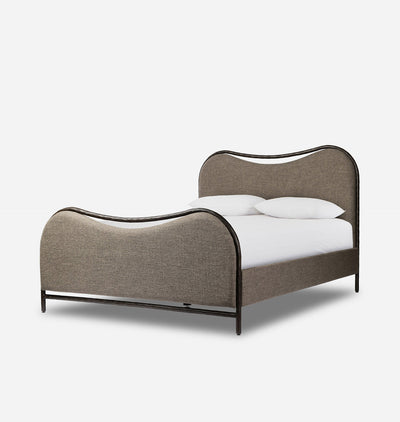 A modern curved bed frame with upholstered taupe fabric and a dark metal frame, shown with white bedding and pillows on a clean white background.