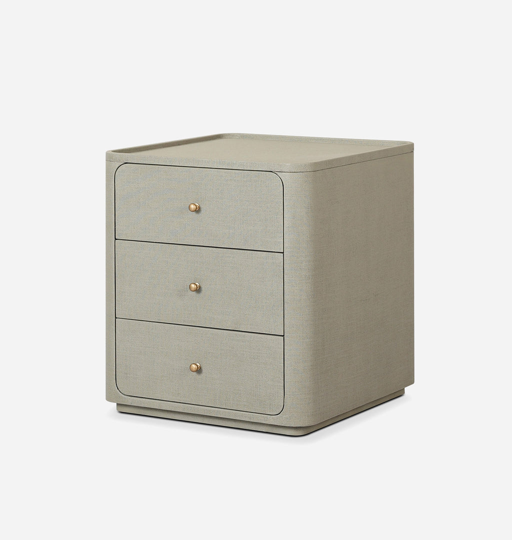 A three-drawer nightstand with a textured light beige linen finish and small round gold knobs, shown on a clean white background.