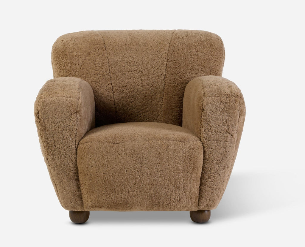 A small upholstered armchair in a textured tan or camel shearling fabric, shown from the front on a clean white background.