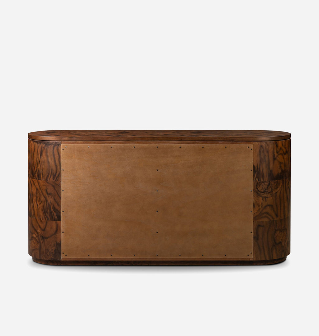 A modernist wooden console table or desk with a curved front, featuring a central tan leather panel and dark brown wood grain side panels, shown against a plain light gray background.