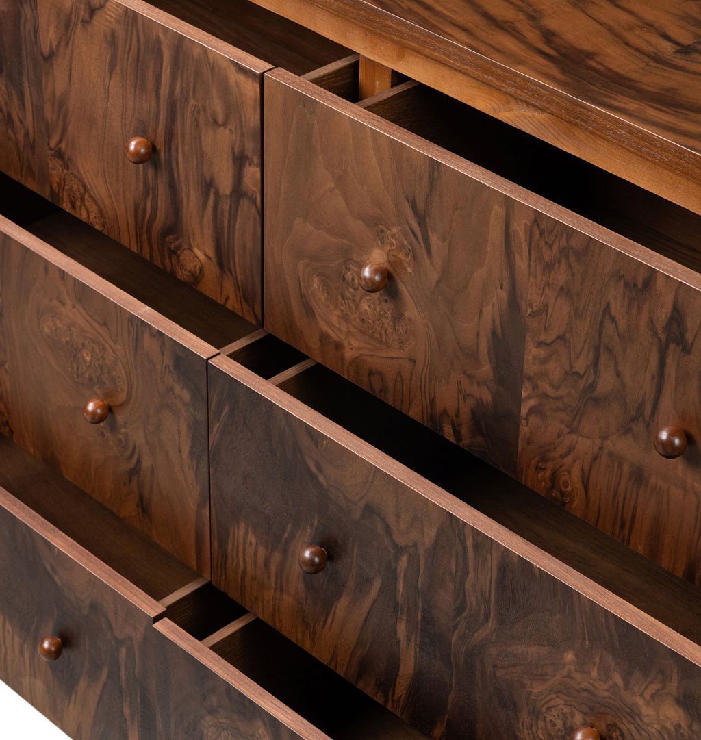 Close-up of a dark brown wooden cabinet or dresser with multiple drawers, each fitted with a small round metallic knob, showing rich wood grain and open drawer fronts.