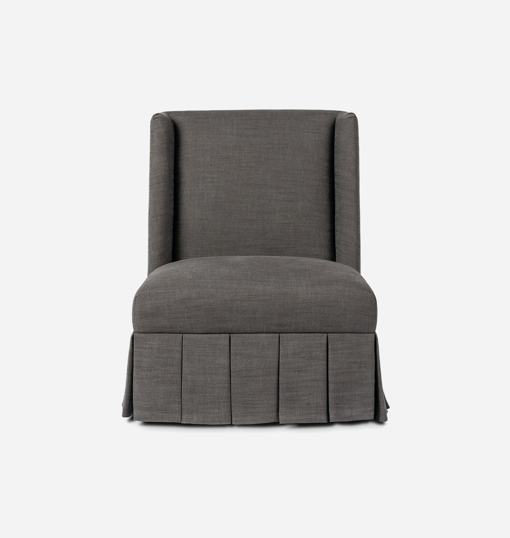 A dark gray upholstered accent chair with a high back, winged arms, and a pleated skirt base, shown against a plain white background.