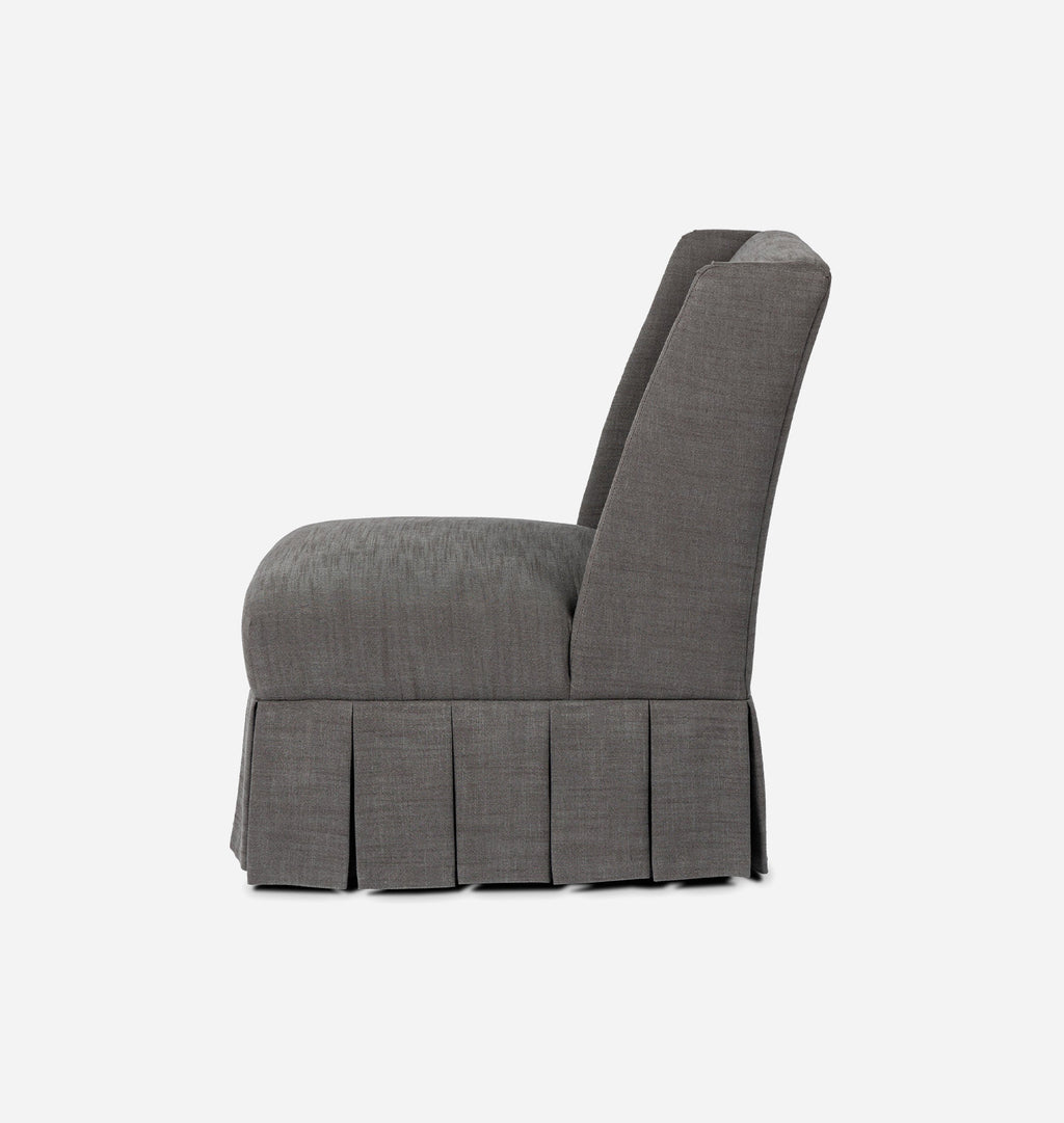 A gray upholstered accent chair with a high back, pleated skirt base, and rounded armrests, shown from a side profile on a light gray background.