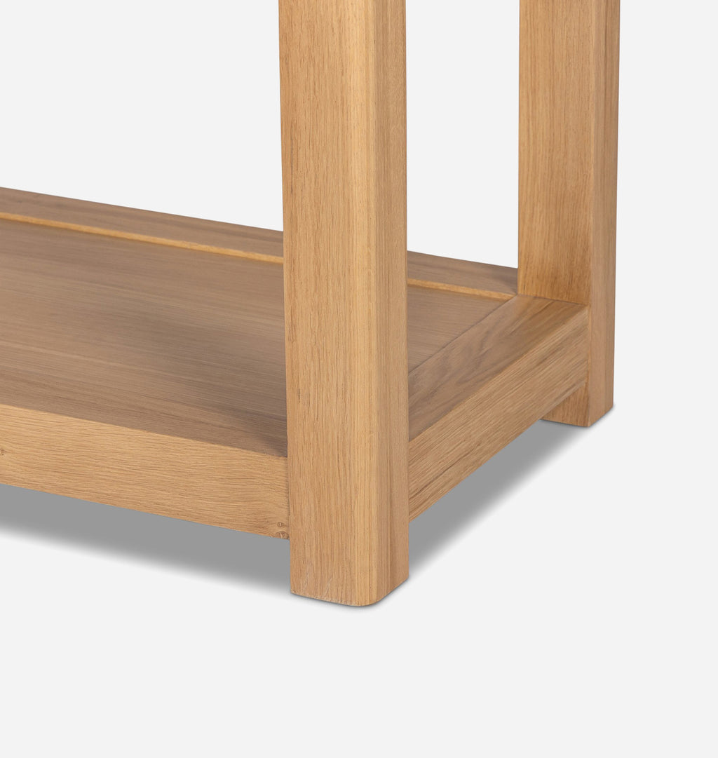Close-up detail of a light oak wood furniture piece, showing the corner joint of a shelf and leg with a clean white background.