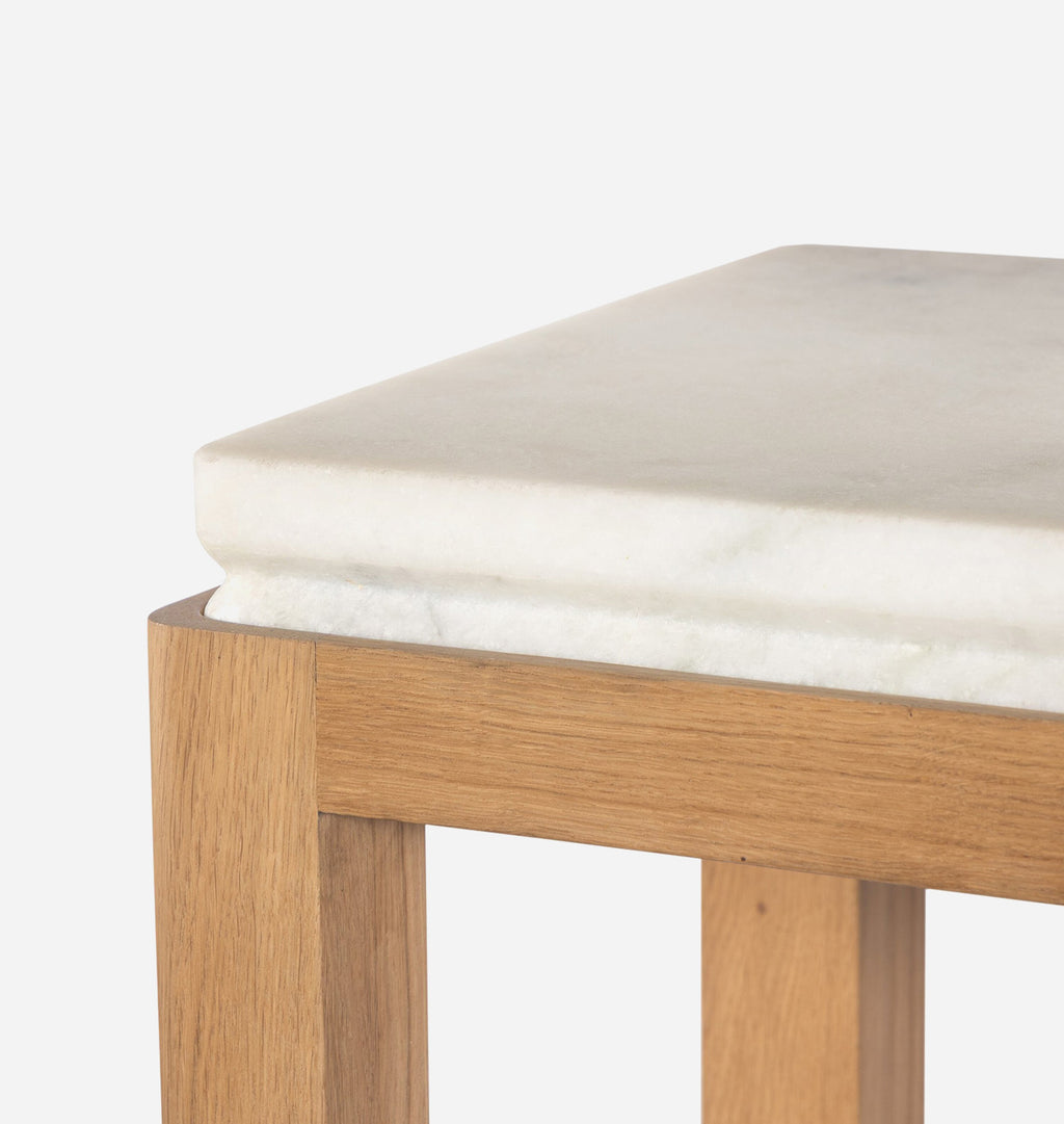 Close-up of a square side table corner showing a white marble top with subtle gray veining and a light natural wood frame.