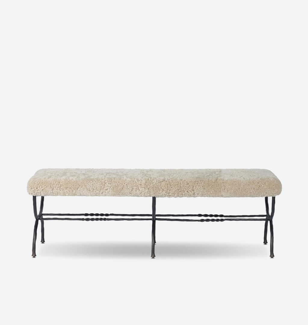 A rectangular bench with a textured cream shearling upholstered seat and a black metal frame with decorative twisted legs, shown against a plain light gray background.