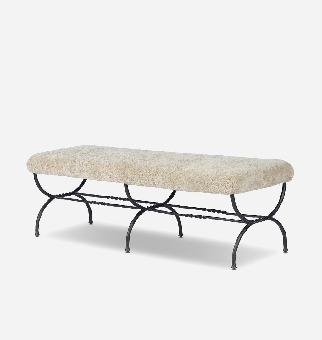 A rectangular bench with a cream-colored sheepskin cushion on a black metal frame, shown against a light gray background.