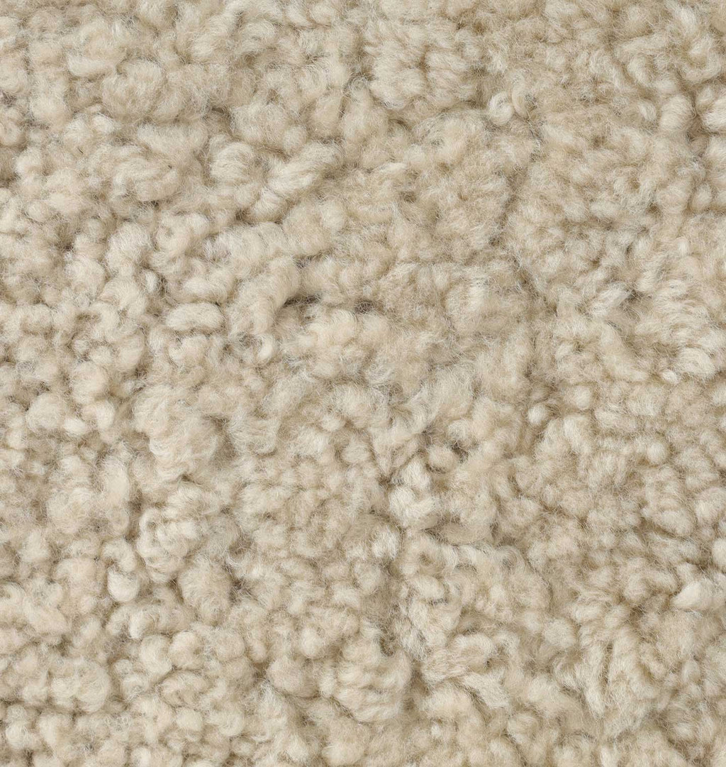 A close-up texture shot of a beige shearling, showing the fluffy, high-pile fibers in detail.